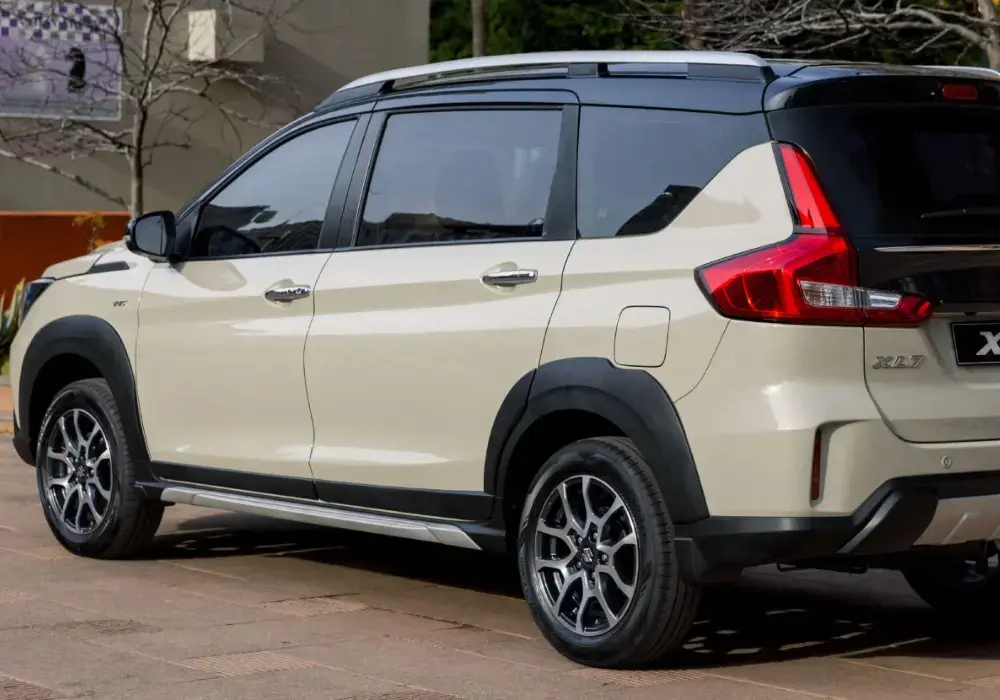 SUV Suzuki XL7 en color beige con detalles negros, vista trasera.