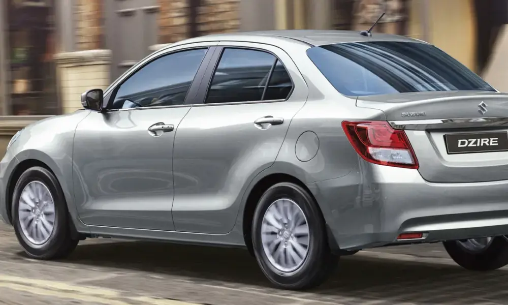 Suzuki Dzire plateado en movimiento, vista trasera.