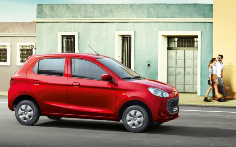 Suzuki Nuevo Alto K10 rojo en movimiento junto a personas caminando