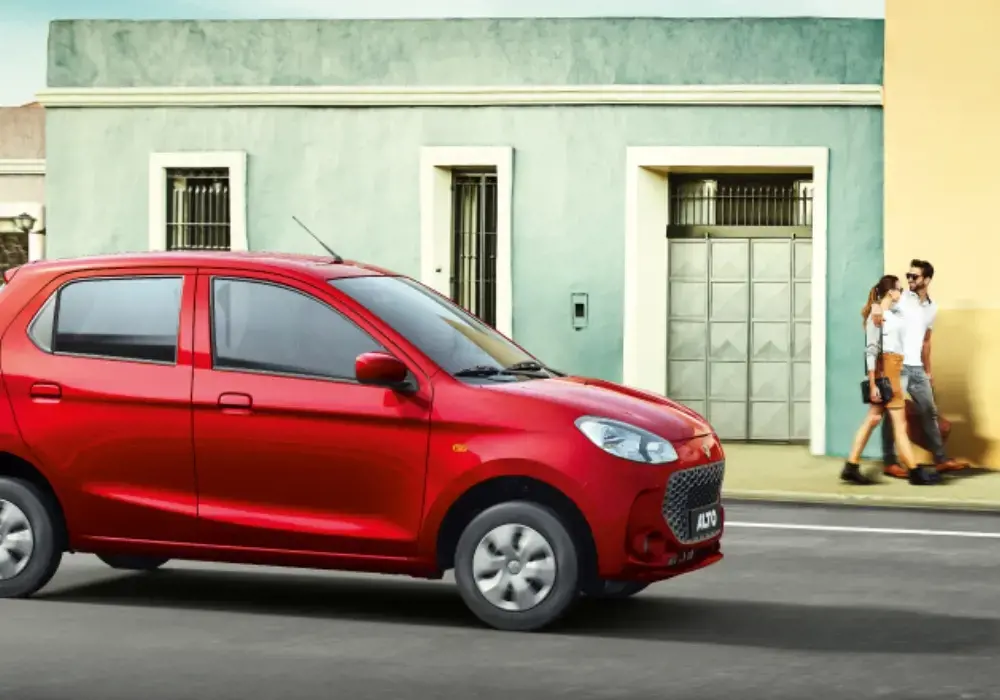 Suzuki Alto rojo estacionado en una calle urbana, con una pareja caminando en el fondo.