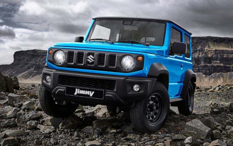 Carro 4x4 Suzuki Jimny azul, modelo de vehículo todoterreno compacto, recorriendo un camino rocoso en un entorno natural.